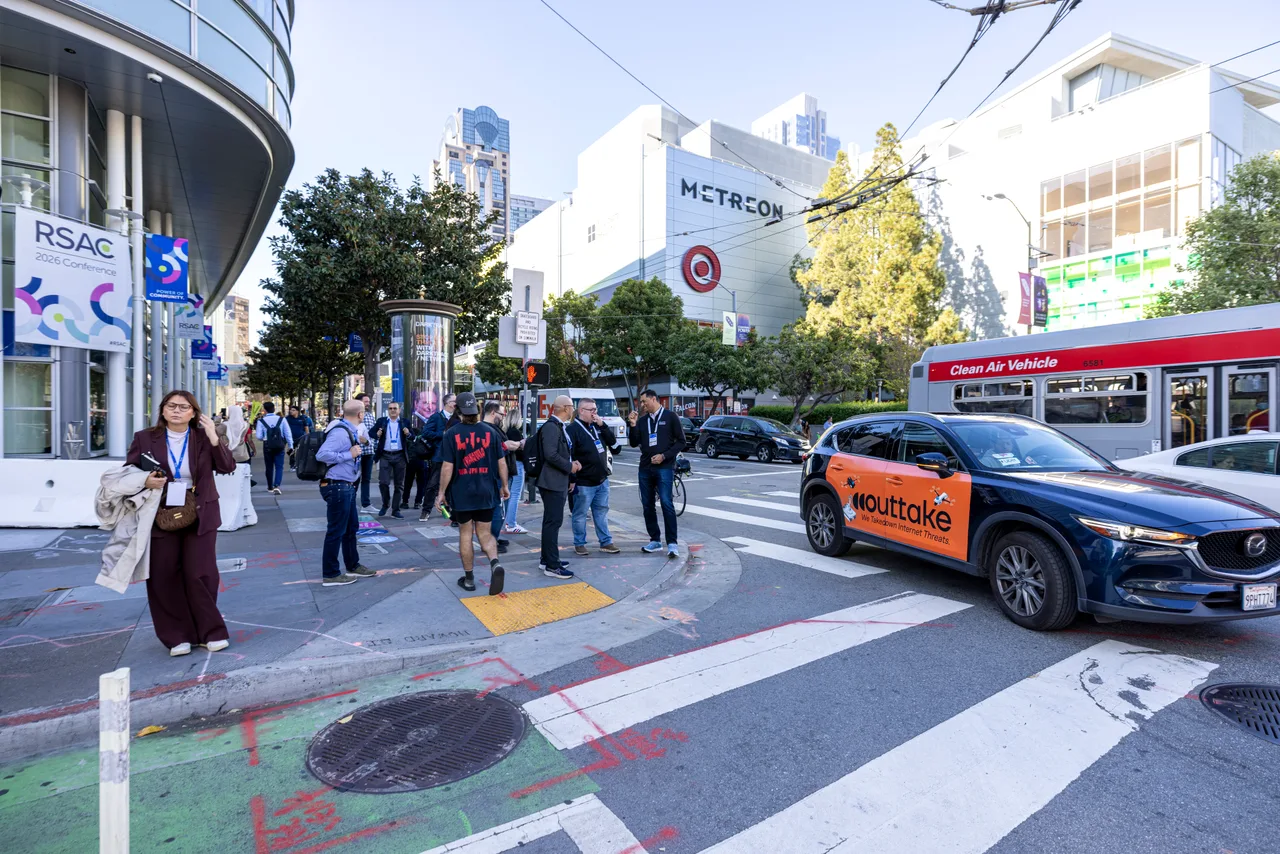 Outtake campaign on a wrapped car at the Metreon at Moscone, beside a Muni bus, San Francisco, 2026