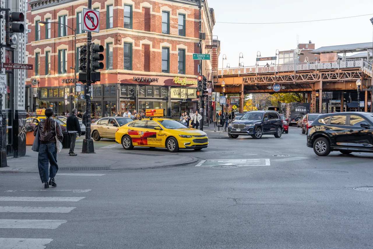 Balloon Museum campaign on a wrapped car carrying a digital top at Damen Avenue under the Blue Line, Wicker Park, Chicago, 2025